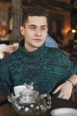 Gülümseyen adam kafede dizüstü bilgisayar kullanıyor.