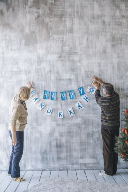 İki yaşlı insanlar Noel çelenk ile ev dekorasyon