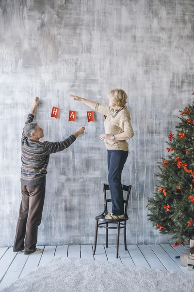 Elderly couple decorating the wall — Stock Photo, Image