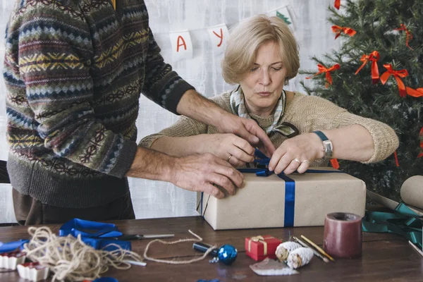 Dos personas mayores decorando regalo de Navidad juntos — Foto de Stock