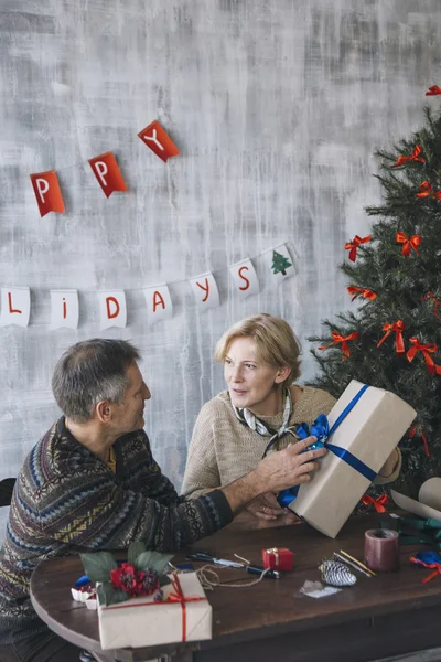 Pareja de personas mayores hablando mientras sostiene regalo de Navidad decorado —  Fotos de Stock