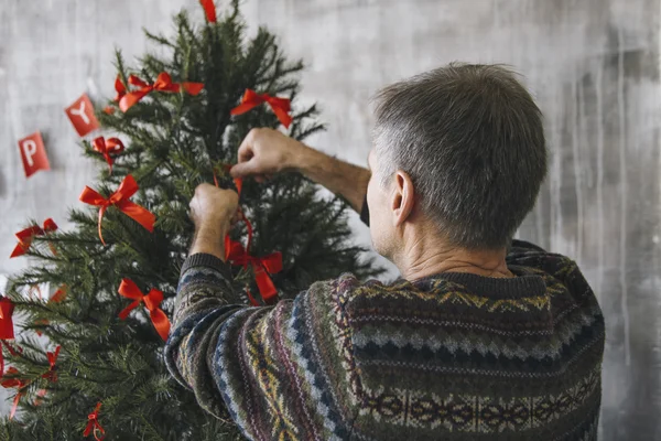 Man decorating the fir-tree with red ribbons — Stock Photo, Image