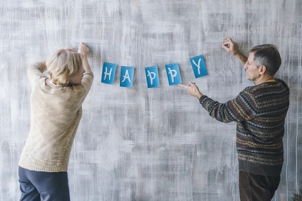 Couple decorating the wall with Christmas garland — Stock Photo, Image