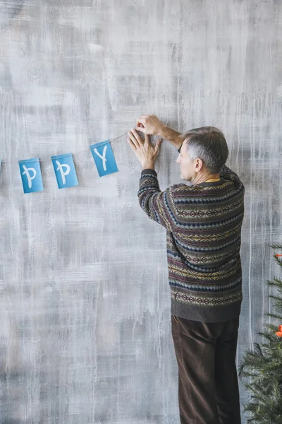 Man decorating wall with blue and white garland — Stock Photo, Image