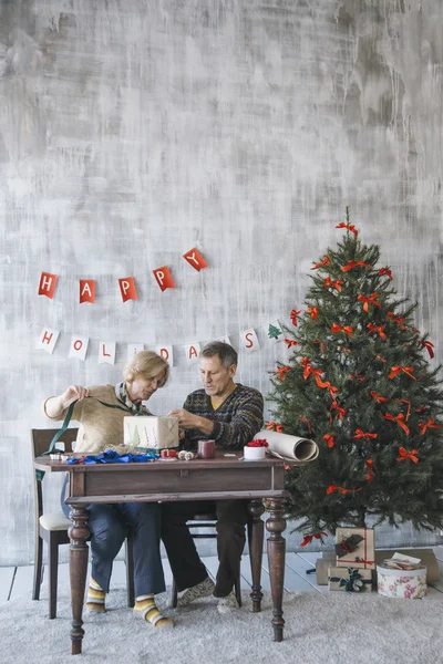 Två äldre människor dekorera julklapp — Stockfoto