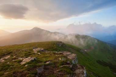 Dağlarda dramatik bir gün batımı. Yaz yağmurundan sonra sis