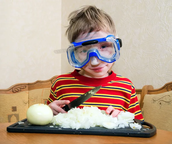 The child cuts the onions. He put on a mask for scuba diving, not to watery eyes. — Stock Photo, Image