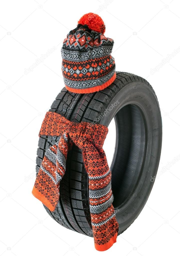 Rubber tire with a knotted scarf and winter hat. Isolated.
