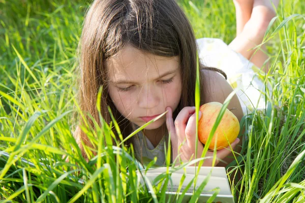 Fille couchée sur l'herbe livre de lecture — Photo