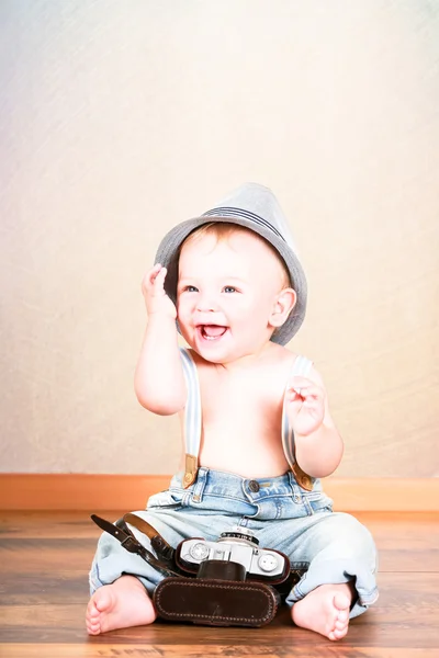 Niño sonriente sentado con cámara fotográfica — Foto de Stock