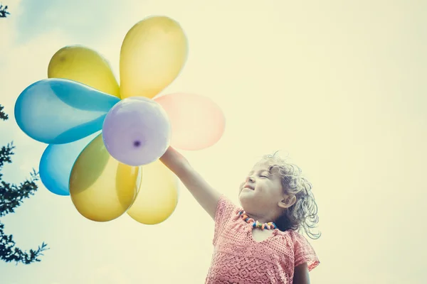 Liten flicka med färgglada ballonger — Stockfoto