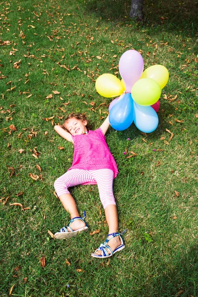 Niña graciosa acostada en la hierba en el parque —  Fotos de Stock