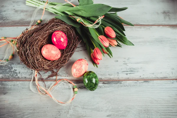 Huevos de Pascua en el nido y tulipanes — Foto de Stock