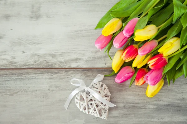 Wooden background with tulips and heart — Stock Photo, Image