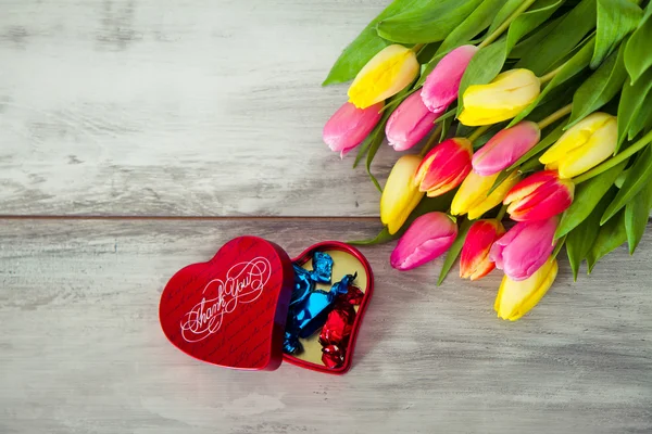 Doos van chocolade en tulpen — Stockfoto