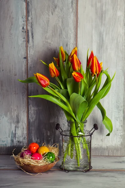 Tulipani rossi e piatto con uova di Pasqua — Foto Stock