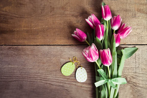 Tulips and decorated eggs on wood background — Stock Photo, Image