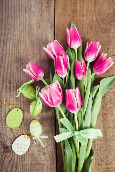 Tulips and decorated eggs on wood — Stock Photo, Image