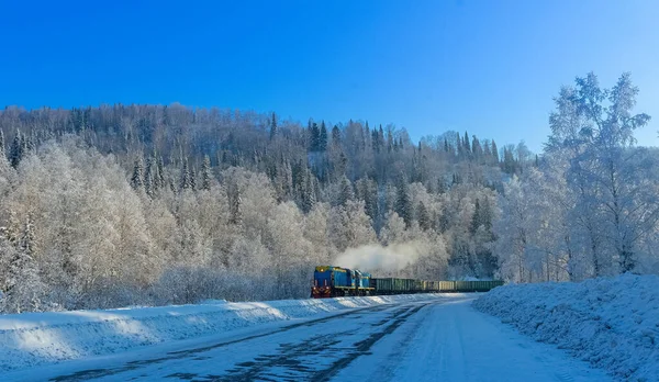 Buharlı lokomotifli kış manzarası bir tren dolusu arabayı çekiyor..