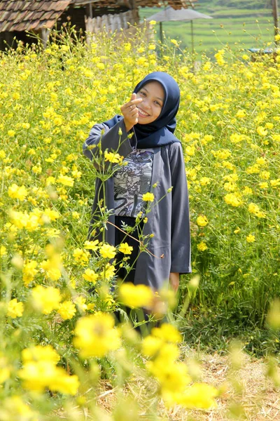 Sarı bir çiçek bahçesinde poz veren Asyalı bir kadının portresi. Hafta sonu doğa turizminin tadını çıkarın.
