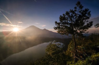 Menjer Gölü 'nün güzelliği Sindoro Dağı' nın arka planında. Wonosobo turizm merkezi, Java. Manzaranın silueti, arka planda parlayan güneş ışığına karşı.