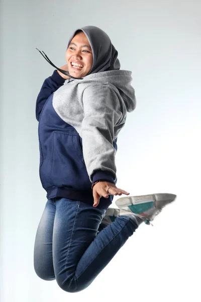 Sıradan kıyafetler giyen Asyalı bir kadının portresi. Beyaz arka planda gri ceket giyen kapüşonlu kadın. Mutlu ifade ile havada asılı fotoğraf konsepti