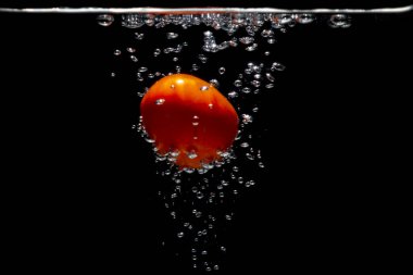 Su kabarcıklı taze kırmızı domates. Sudaki meyvenin tazeliği kavramı. İzole edilmiş siyah arkaplan ile sualtı sebze fotoğrafı