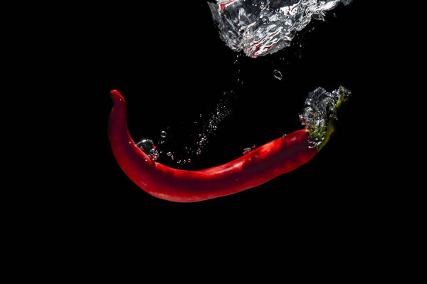 fresh red chilies with water bubbles. the concept of freshness of fruit in water. underwater vegetable photo with isolated black background