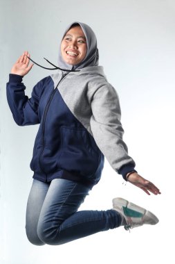 Sıradan kıyafetler giyen Asyalı bir kadının portresi. Beyaz arka planda gri ceket giyen kapüşonlu kadın. Mutlu ifade ile havada asılı fotoğraf konsepti