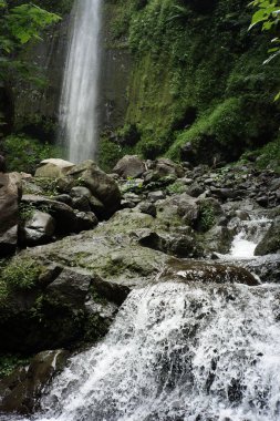 Şelale manzarası ve ormanın ortasındaki akan nehirler. Yağmur mevsiminde tropikal doğanın tazeliğinin rahatlaması. Şelale turunu süsleyen büyük kayalar.