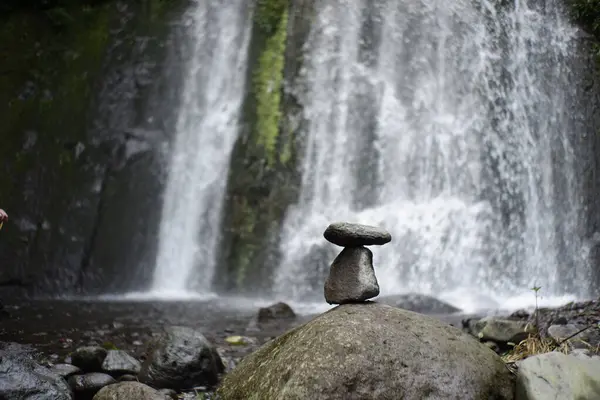 play rock balance in the river water flow. relaxation in the cool tropical wilderness. rock balance with waterfall background