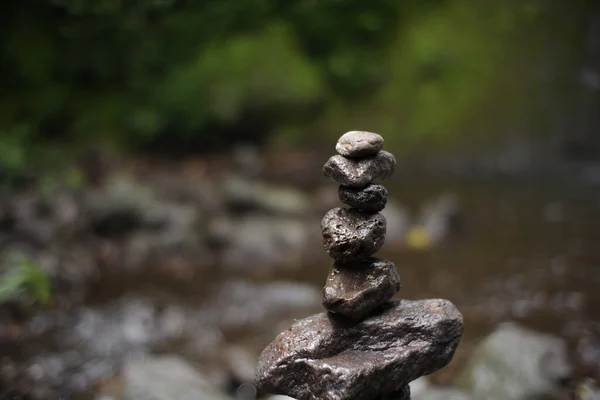 play rock balance in the river water flow. relaxation in the cool tropical wilderness. rock balance with waterfall background