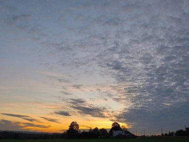 Sunset on the horizon and a mountain range of sheep clouds
