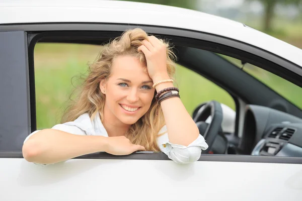 Щаслива блондинка в гетеровій новій білій машині — стокове фото