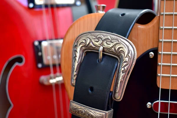 Electric guitars and leather strap with silver buckle close-up.