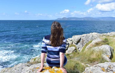 Woman on a cliff looking at the view at famous Rias Baixas in Galicia Region, Spain.