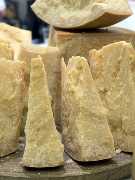 Толстые ломтики итальянского сыра пармезан на деревянной доске — стоковое фото