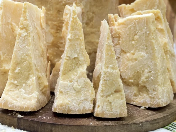 Thick slices of Italian Parmesan cheese on a wooden cutting boar — Stockfoto