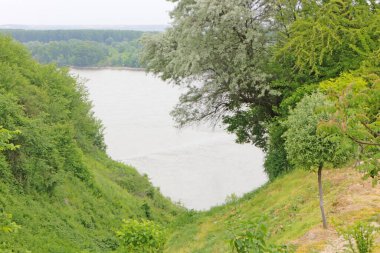 Geniş nehir, gri gökyüzü ve beyaz bulutlar.