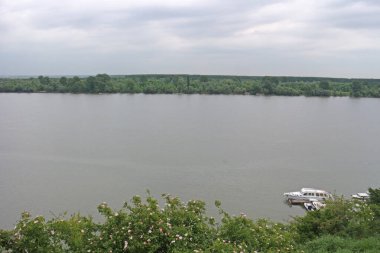 Geniş nehir, gri gökyüzü ve beyaz bulutlar.