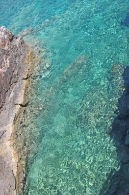 Yeşil, kristal berrak deniz suyu ve kayalar