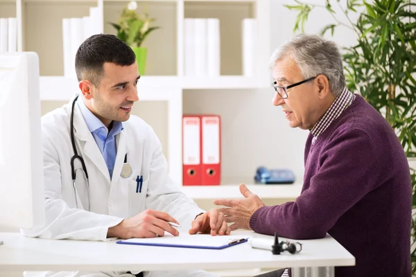 Arzt hört Patient zu, wie er seine Schmerzen erklärt — Stockfoto