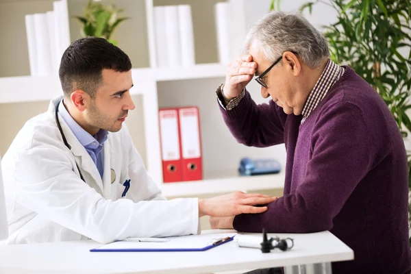Doctor listening to patient explaining his painful — ストック写真