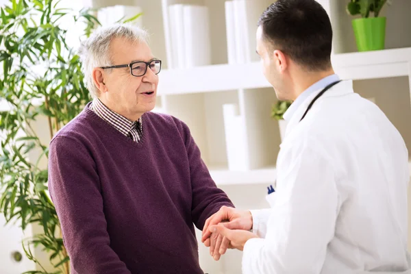 Dokter muda memegang tangan berbicara dan santai pasien tua — Stok Foto