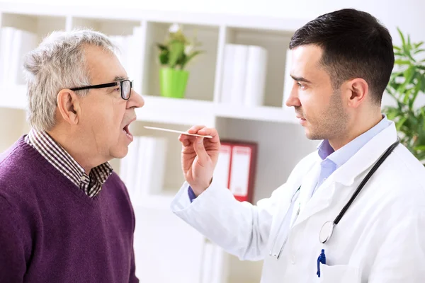 Doctor examining old patient throat — Stock Photo, Image