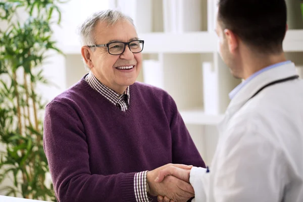 Smiling happy healthy old male shaking with doctor — Stock Photo, Image
