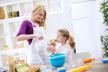 Anne ve kızı bir pastada süt koyun