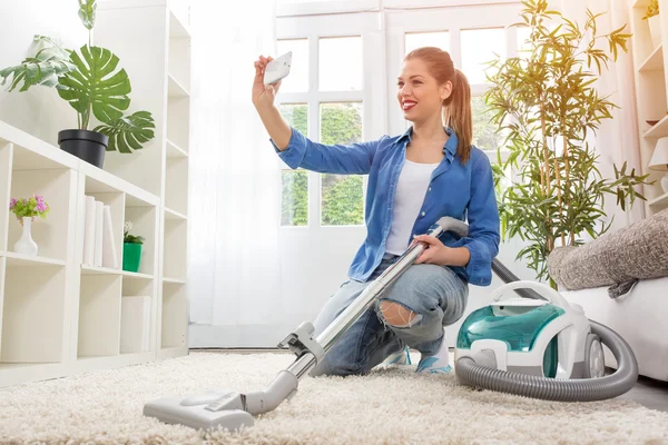 Frau mit Staubsauger putzt Teppich und macht Selfie — Stockfoto