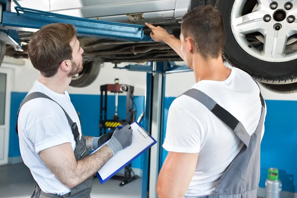 Mecánica de taller de automóviles inspeccionando daños al coche — Foto de Stock