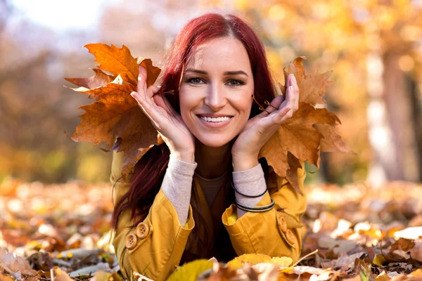 Ragazza felice sdraiata in foglie d'autunno — Foto Stock